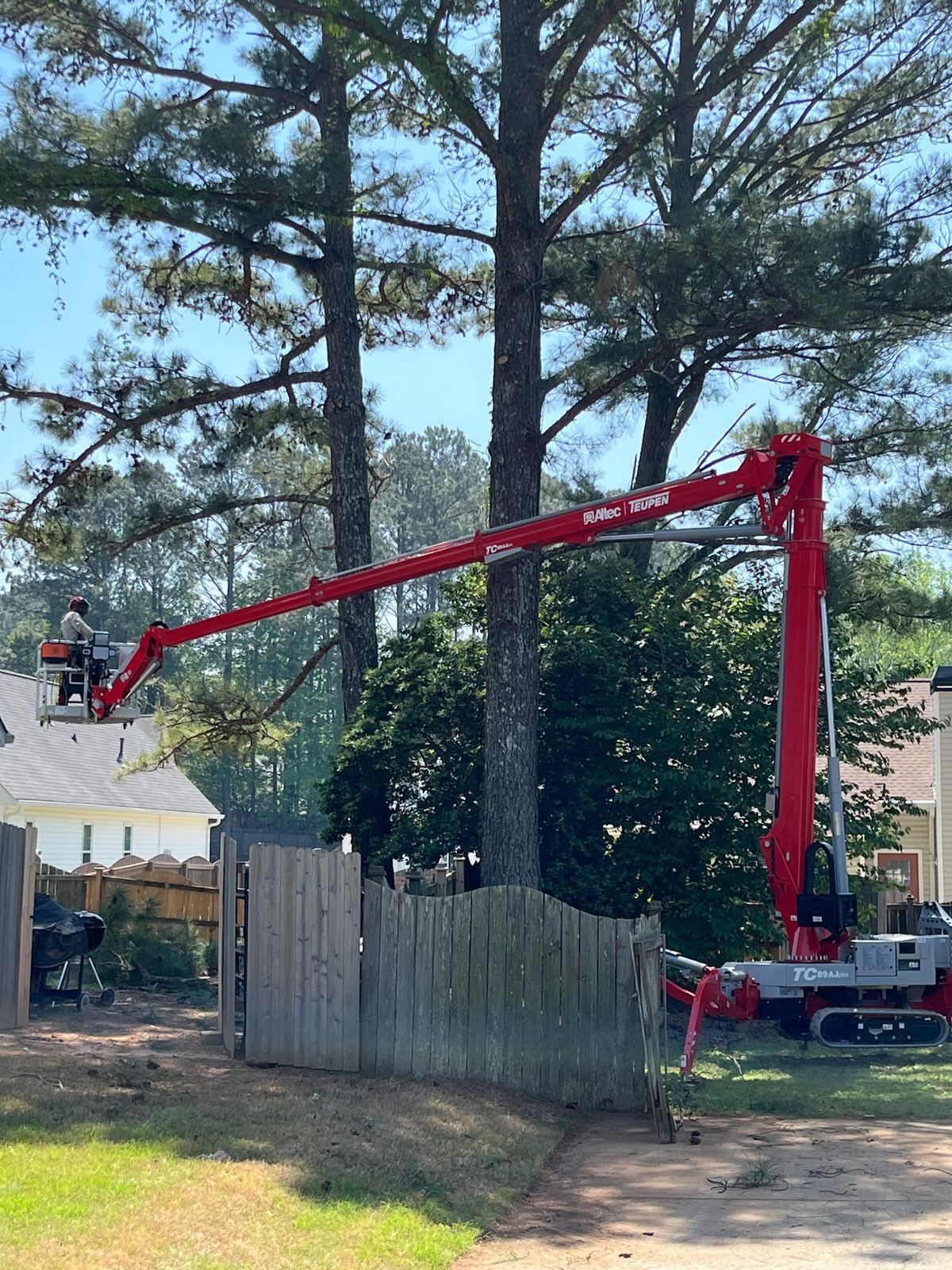 Lift reaching over a privacy fence into a tight backyard